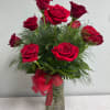 Red roses arranged in a clear glass vase with a red ribbon
