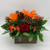 Orange lilies and red roses arranged in a wooden box