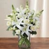 White lilies and roses arranged in a clear glass vase