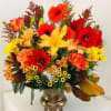 Bright mixed flower arrangement in a gold vase with red, orange, and yellow blooms