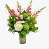 Tall mixed bouquet of pink and white flowers in a clear glass vase