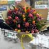 Bouquet of pink and yellow tulips wrapped in paper with a yellow ribbon