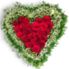 Heart-shaped arrangement of red roses with a green and white floral border