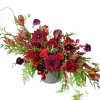 Red and burgundy floral arrangement in a gray vase
