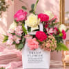Pink and white flower arrangement in a white gift bag with roses and carnations
