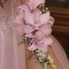 Pale pink dendrobium orchids curve gently along the wrist in this elegant