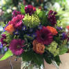 Mixed bouquet of magenta, orange, and purple flowers in a glass vase