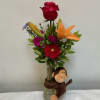 A bright red rose crowned at the top and a playful plush