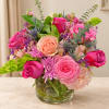 Pink and peach roses in a clear glass vase with purple accents