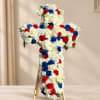 Cross-shaped floral tribute with white, red, and blue flowers on an easel