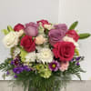 Mixed bouquet of roses, lilies, and daisies in a glass vase