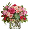Pink roses and carnations in a glass vase with a succulent accent
