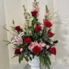 Tall bouquet of red roses, pink lilies, and carnations in a white vase