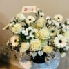 Cream roses and white daisies arranged in a black vase