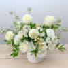 White floral arrangement in a white vase with roses and round blooms