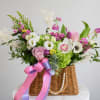 Mixed pink and white flowers in a wicker basket with ribbon