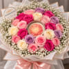 Bouquet of pink, cream, and lavender roses around a flower-shaped candle
