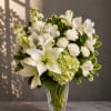 White lilies and mixed white flowers in a clear glass vase