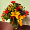 Mixed bouquet of red, yellow, and orange flowers in a glass vase