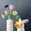 Two small floral arrangements in white vases with pink and white blooms