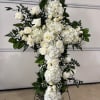 White floral cross arrangement with roses and hydrangeas on a stand