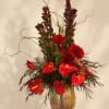 Red gerbera daisies and anthuriums in a glass vase
