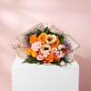 Bouquet of orange and pink roses wrapped in white paper