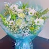Bouquet of white daisies and pale blue flowers wrapped in blue cellophane