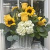 Yellow roses, sunflowers, and white hydrangeas arranged in a metal bucket-style vase