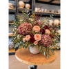 Large mixed floral arrangement in a textured vase on a round table