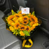 Bouquet of yellow sunflowers and roses wrapped in black paper