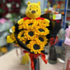 Winnie the Pooh plush holding a sunflower bouquet with a red ribbon
