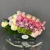 Pink and cream roses with purple orchids in a glass vase