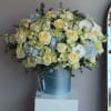 Large bouquet of cream roses, blue hydrangeas, and white orchids in a blue hatbox
