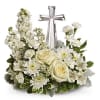 White floral arrangement with roses and daisies around a silver cross