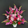 Large pink and red floral arrangement in a white vase
