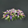 Pink and purple floral casket spray with white lilies and ribbon