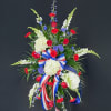 Standing floral spray with red roses, white hydrangeas, and blue accents