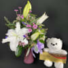 Bouquet of white lilies and pink flowers in a vase with a teddy bear and chocolates