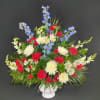 Red, white, and blue floral arrangement in a white vase