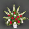 Red roses and white flowers in a white vase with greenery