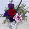 Red rose and purple tulip arrangement in a printed ceramic vase