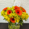 Orange gerbera daisies and yellow alstroemeria in a glass vase