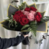 Bouquet of red and pink roses wrapped in black paper with gold trim