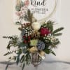 Holiday bouquet in a glass vase with roses, pinecones, and evergreen sprigs