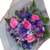 Bouquet of pink roses and purple flowers wrapped in translucent paper