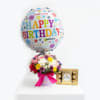 Birthday balloon above a mixed flower arrangement with a chocolate box