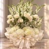 Cream floral arrangement with roses and hydrangeas in a wrapped base
