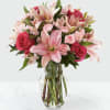 Pink lilies, roses, and carnations in a clear glass vase