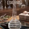 Clear glass cross on a wooden table beside a gift box